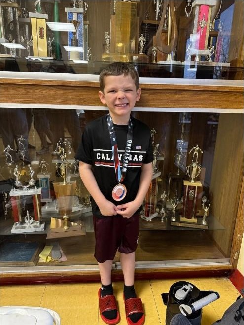 Medal winner in front of the trophy case